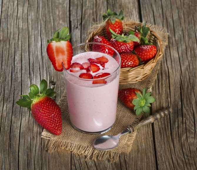 Strawberry yogurt in a glass with fresh strawberries on a wooden table