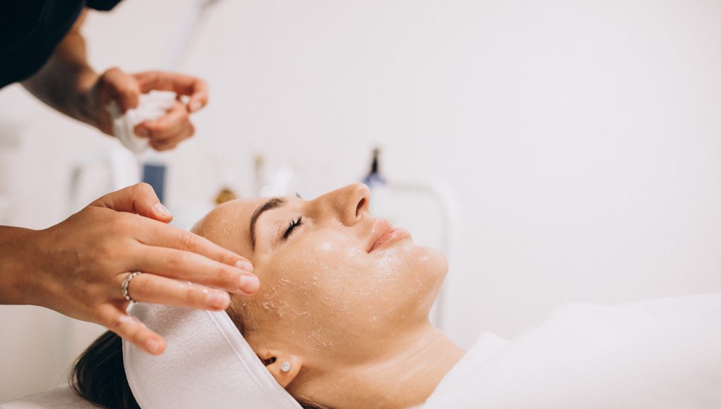 Cosmetologist cleaning face of a woman in a beauty salon