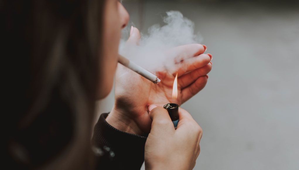 Selective closeup shot of a female lighting up a cigarette with a lighter