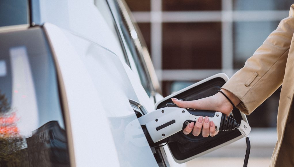 Woman charging electro car at the electric gas station