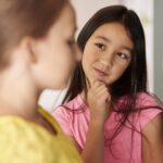 Girl with hand on chin looking at classmate