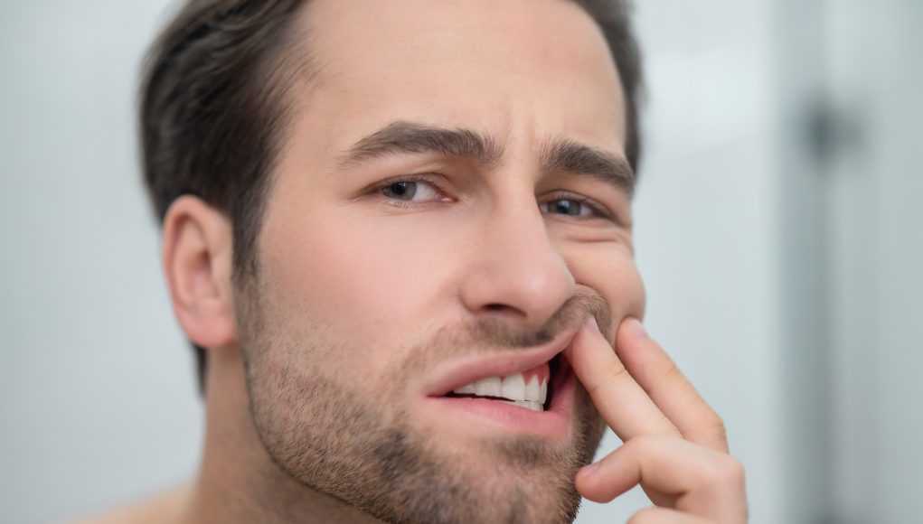 Man checking his teeth and looking disturbed