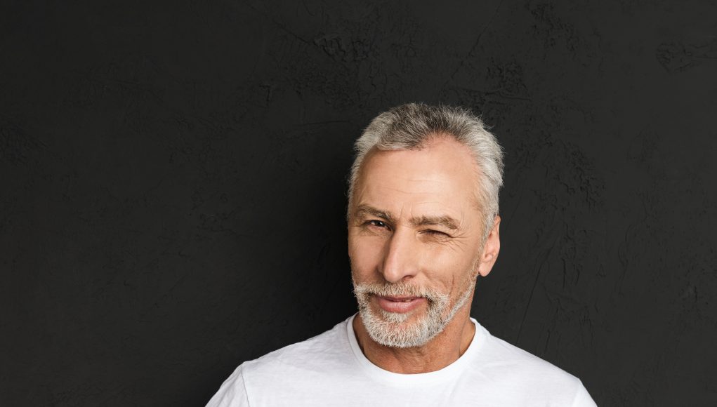 Cheerful mature old man winking.