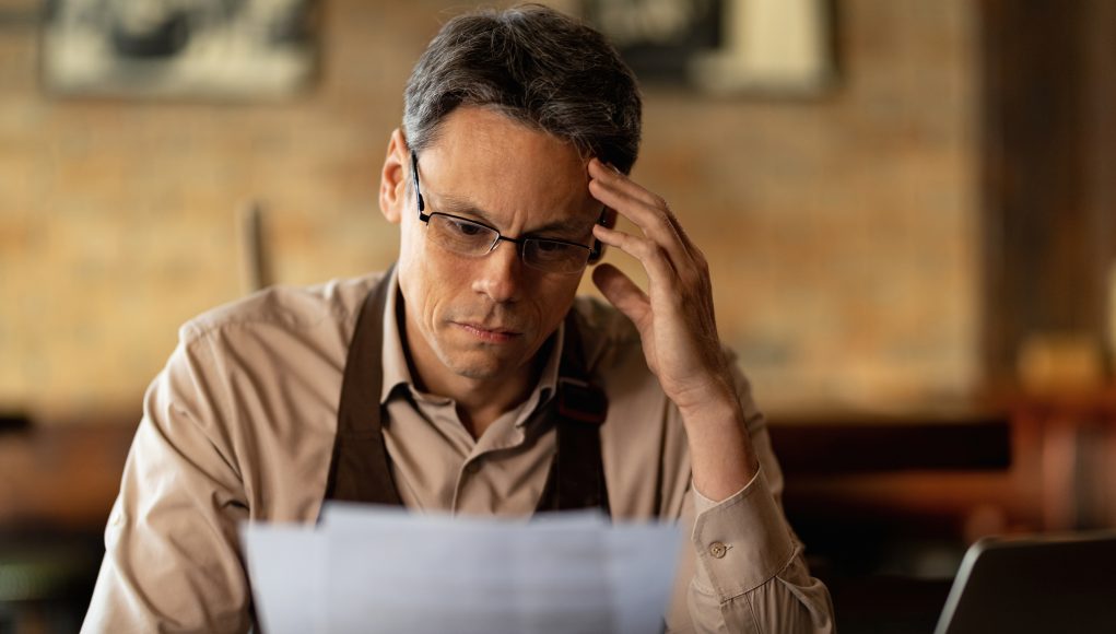 Worried barista analyzing paperwork in a pub.