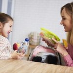 Mum putting lunch box with healthy food in backpack
