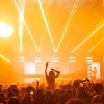 Beautiful shot of a live concert performance with a yellow light show and a big crowd cheering