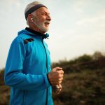 Happy senior runner jogging in nature in the morning.