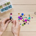 person-s-hand-sticking-beads-metal-bangle