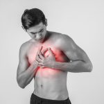 Young man has heart attack isolated on white background.