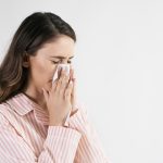 Young woman blowing her nose in studio shot