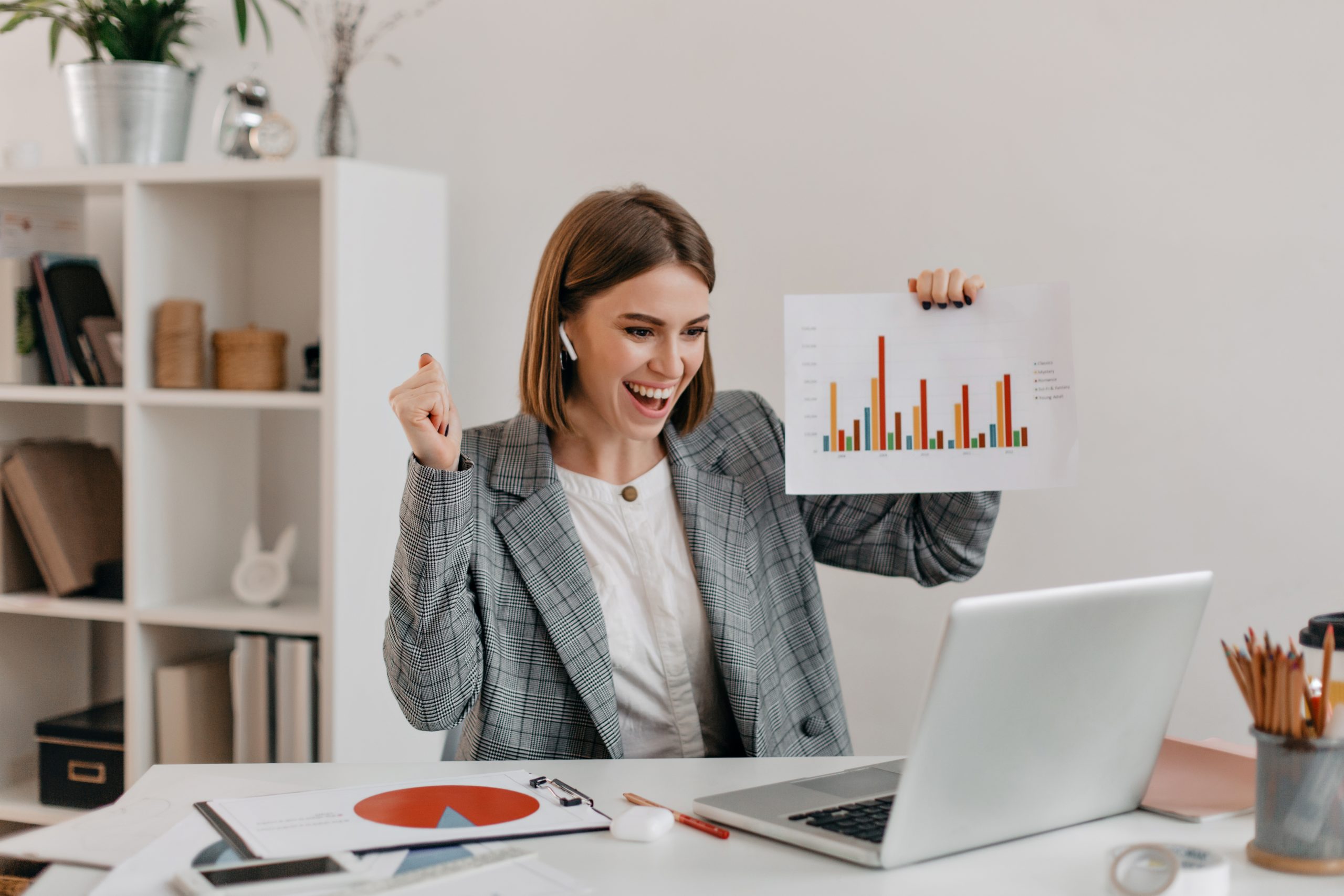 Close-up shot of happy business woman in stylish outfit. Girl in high spirits demonstrates chart via Skype.