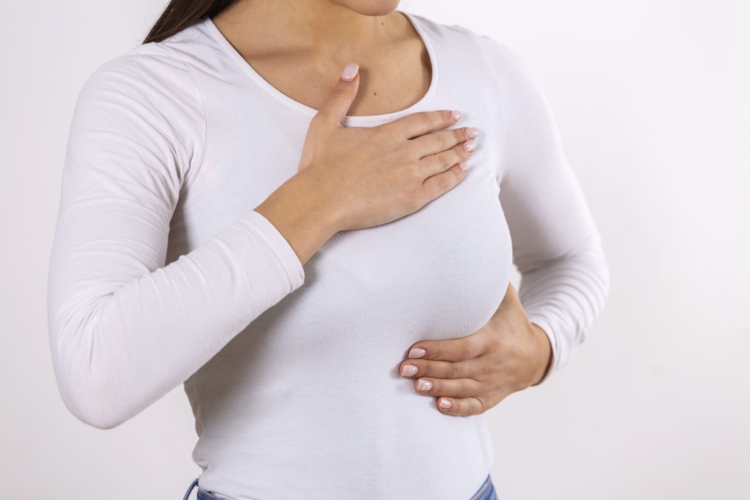 Woman hand checking lumps on her breast for signs of breast cancer on gray background. Healthcare concept. Close-up Of A Woman's Hand On Breast Showing Cancer Symptom